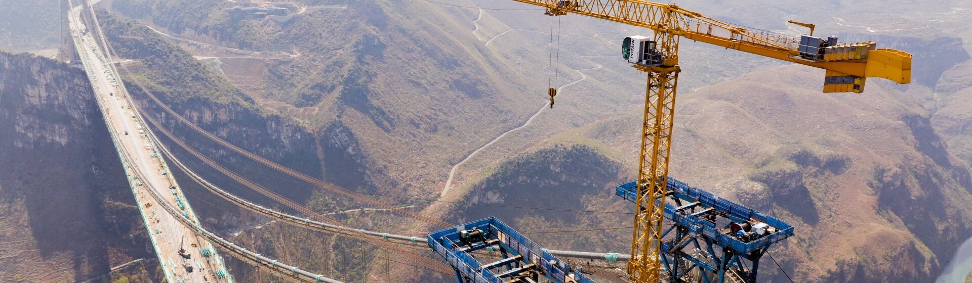 The Potain MCT 385 standing tall over the Huajiang Grand Canyon, supporting construction of the world’s tallest bridge. Potain-MCT-385-hits-new-heights-on-worlds-tallest-bridge-1.jpg